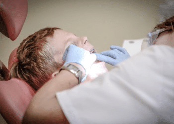private dentists - a dentist examines the teeth of a young boy