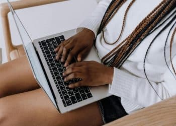 Woman uses her laptop which is rested on her outstretched legs - DWP