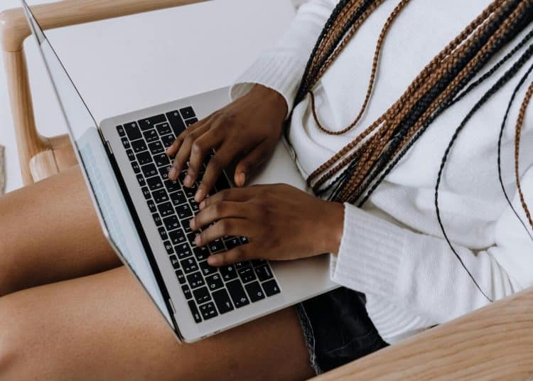Woman uses her laptop which is rested on her outstretched legs - DWP
