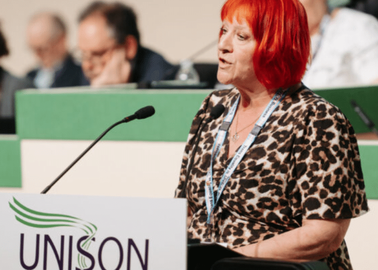 Andrea Egan speaking at the 2026 Unison health conference wearing her Unison lanyard and standing infront of a mic