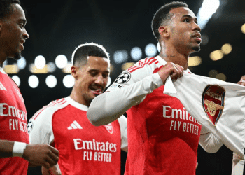 Arsenal players celebrate their 4-0 win over Atletico Madrid in October 2025. One players holds a t-shirt with the Arsenal emblem printed on it