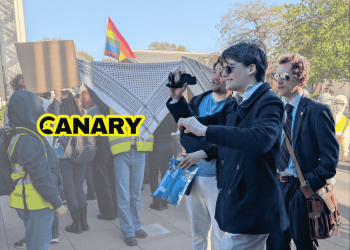 Picture of newly ratified York University Restore Britain Society members filming and jeering at student protesters. The Canary logo is on the left and in the background is an image of protesters holding up Keffiyehs to hide attendees.