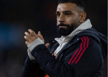 Liverpool player, Mo Salah, claps his hands together and looks somewhat morose looking on in the distance