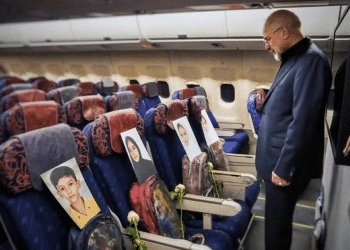 A man looks at photos of the children lost in the Minab tragedy in Iran