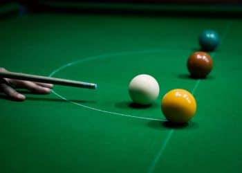 A snooker cue aims at balls on a snooker table