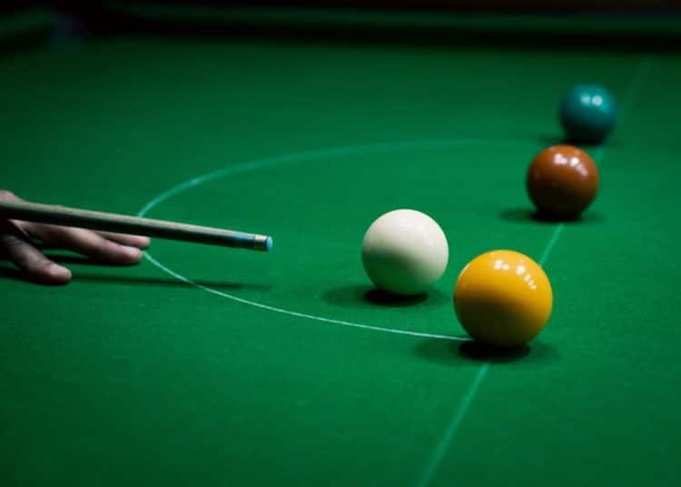 A snooker cue aims at balls on a snooker table