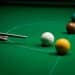A snooker cue aims at balls on a snooker table
