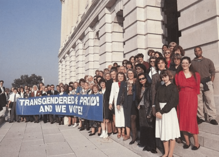 Archive photo of a line of people holding a banner that says 'Transgender and proud! And we vote'.