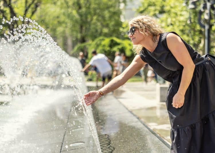 A woman cools down at a city centre cooling fountain Climate adaptation