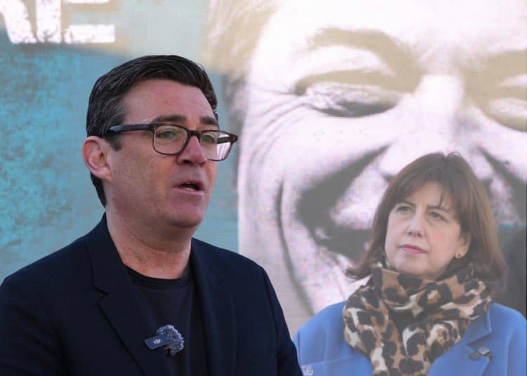 Manchester Mayor Andy Burnham speaks with Deputy Leader of the Labour Party Lucy Powell looking on in front of a anti Reform UK poster with a picture of Leader Nigel Farage as Labour launches its local election campaign In Bury on April 02, 2026 in Prestwich, England.