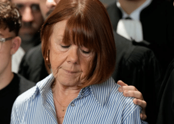 Gisele Pelicot, with her head and gaze down towards the floor and her son's hand on her shoulder, gives a statement inside the courthouse after a verdict in the Pelicot case on December 19, 2024 in Avignon, France. Gisele Pelicot's ex-husband, Dominique Pelicot, and 50 other men were convicted on charges of raping her over a multiyear period, in encounters arranged by Mr. Pelicot while she was drugged and unconscious.