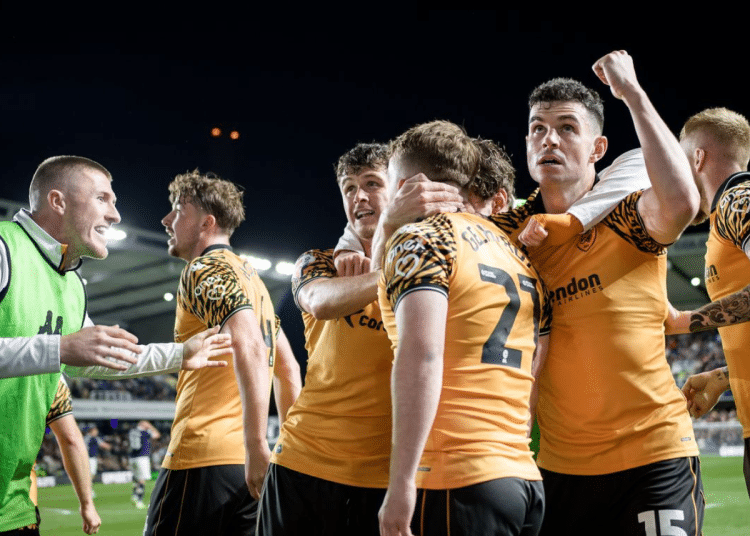 Hull City AFC players hug one another in celebration on the pitch