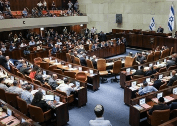 A view of the Knesset in Israel with people sat on the pew-type chairs inside with only the backs of their bodies visible