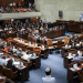A view of the Knesset in Israel with people sat on the pew-type chairs inside with only the backs of their bodies visible