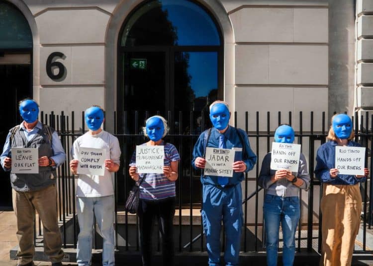 Protesters wearing blue masks outside Rio Tinto office.