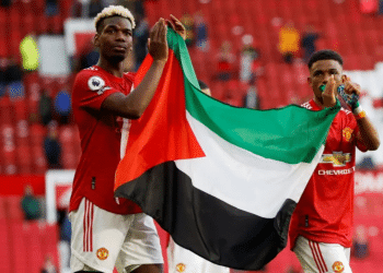 Manchester United's Paul Pogba (left) and Amad Diallo (right) applaud fans while holding a Palestinian flag in May 2021