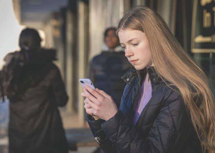 A girl looks at a mobile phone Online misogyny Barnardo's