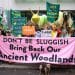 Campaigners dressed as slugs outside Defra holding a banner saying Don't Be Sluggish Bring Back Our Ancient Woodlands