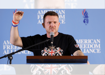 Tommy Robinson holding his hand up