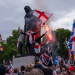 People, largely white men, sit on a Winston Churchill statue with flares and wearing Union Jack, England and Scotland flags as they take part in the rally where Muslims experienced hate speech