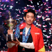Wu Yize holds his 2026 World Snooker Championship trophy while confetti falls around him. Yize has the China flag draped over his suit.