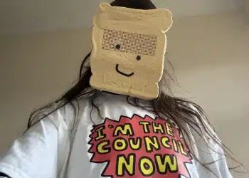 Zöe Bread wearing a sliced white bread mask and a comic style slogan tshirt saying, 'I'm the council now'.