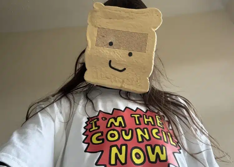 Zöe Bread wearing a sliced white bread mask and a comic style slogan tshirt saying, 'I'm the council now'.