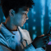Social media: Side view of teenage boy using phone against a digital tech backdrop