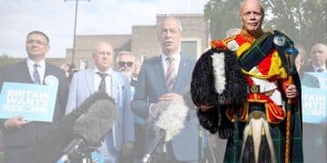 Reform UK candidate Andy Curwen, dressed in his regalier, and in the background, another image of Nigel Farage and other Reform members