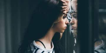 Stock image of girl looking through window, illustrating mental health outcomes