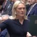 Lara Bird with her right hand in the air in Parliament and her three middle fingers appear to be crossed