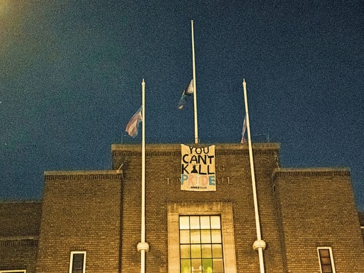 Havering Town Hall with Pride and Trans flags flying from flagpoles and a banner saying YOU CAN’T KILL PRIDE - XOXO TKDB