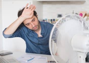 A person looking hot while working, with a fan on the desk Heat Strike