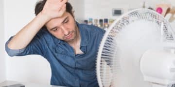 A person looking hot while working, with a fan on the desk Heat Strike