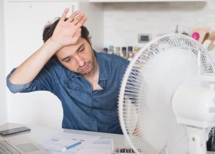A person looking hot while working, with a fan on the desk Heat Strike