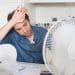 A person looking hot while working, with a fan on the desk Heat Strike