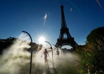 People walk under cooling sprays in front of the Eiffel Tower during a heatwave in Paris