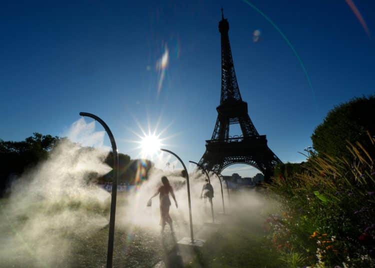 People walk under cooling sprays in front of the Eiffel Tower during a heatwave in Paris