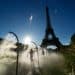 People walk under cooling sprays in front of the Eiffel Tower during a heatwave in Paris