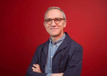 A professional portrait of James Purnell, with his arms folded against a red background. Andy Burnham has appointed him as chief of staff.