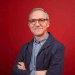 A professional portrait of James Purnell, with his arms folded against a red background. Andy Burnham has appointed him as chief of staff.