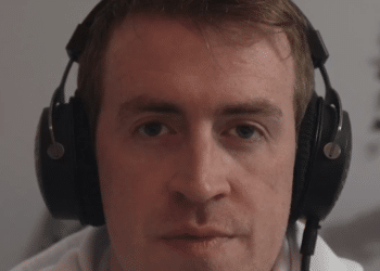 A screenshot of Irish Michael McCarthy speaking on this video, wearing headphones