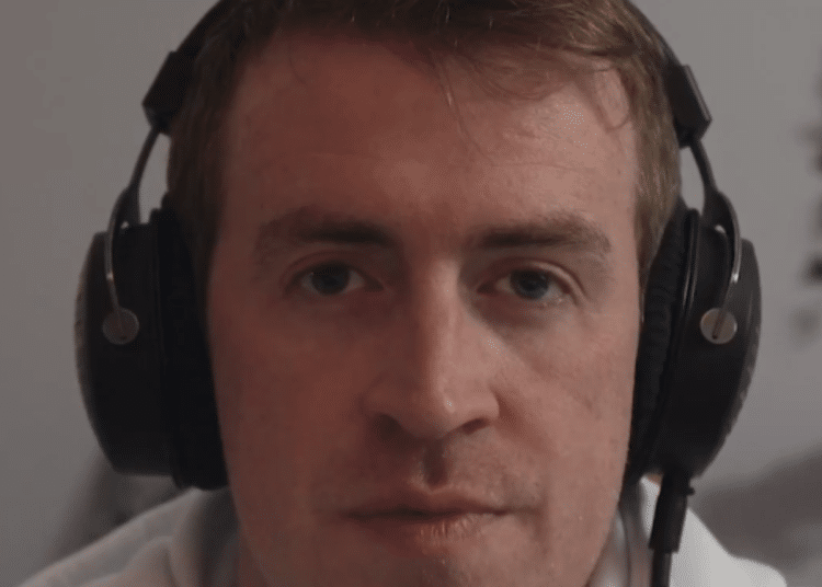A screenshot of Irish Michael McCarthy speaking on this video, wearing headphones
