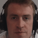 A screenshot of Irish Michael McCarthy speaking on this video, wearing headphones