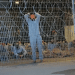 A leaked photograph of the Sde Teiman detention facility shows a blindfolded Palestinian man with his arms above his head behind a metal wire fence in 2024. Knesset politicians defeated a bill to ban visits from the Red Cross.