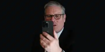 Keir Starmer looking at a phone against a dark background Social media