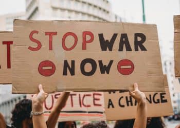 Hands holding a home made placard saying Stop War Now