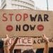 Hands holding a home made placard saying Stop War Now