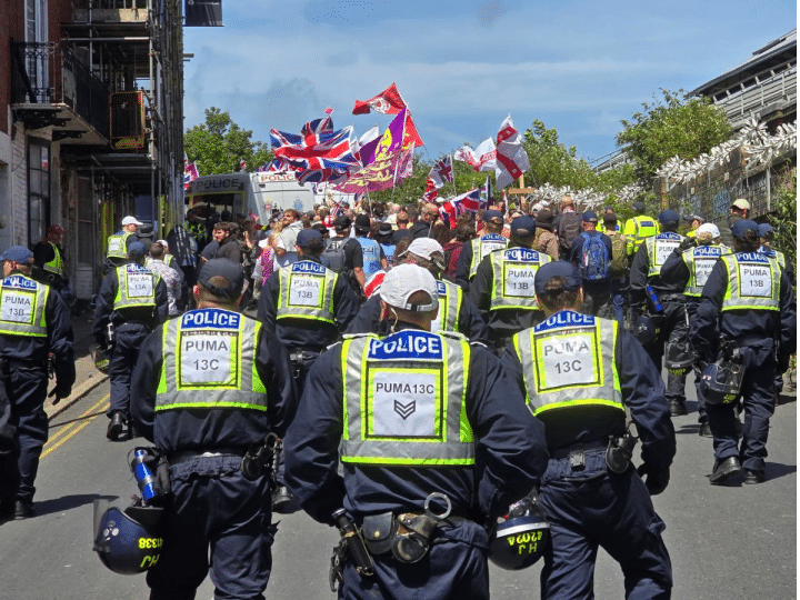 Police from Sussex follow behind protestors raising flags at a protest in Brighton which led to Ryan Bridge being arrested for common assault