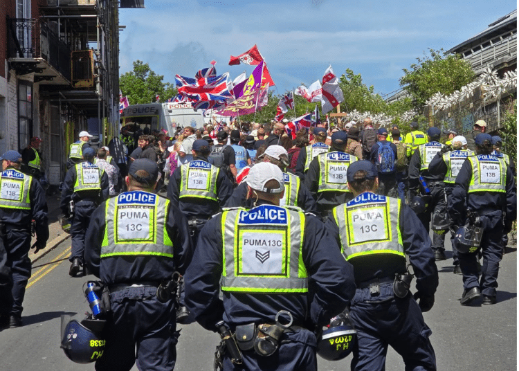 Police from Sussex follow behind protestors raising flags at a protest in Brighton which led to Ryan Bridge being arrested for common assault